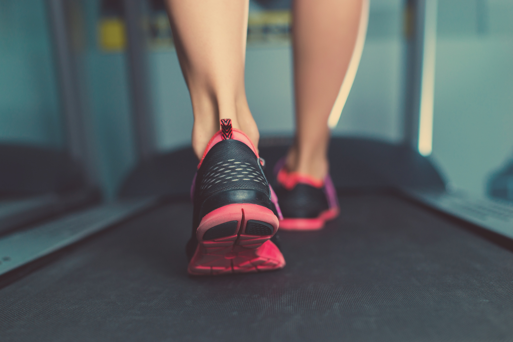 Female muscular feet in sneakers running on the treadmill.